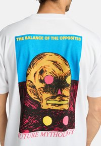 White cotton t-shirt featuring a large graphic print of a skull with colorful circles and text: "THE BALANCE OF THE OPPOSITES" and "FUTURE MYTHOLOGY."