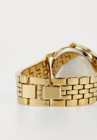 Gold metal watch with a linked bracelet, featuring a smooth finish and rectangular links. The watch case has a circular glass face.