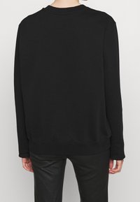 Svart sweatshirt med rund hals, långa ärmar, ribbade muddarna och fållen; tillverkad av mjukt material med en slät textur.