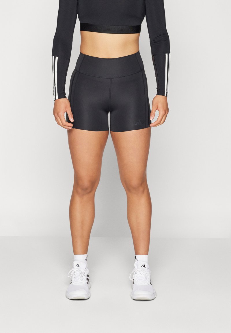 Pantaloni sportivi neri realizzati in materiale elasticizzato, con elastico in vita e un logo del marchio discreto nella parte anteriore. Texture liscia.