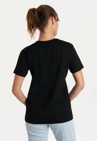 Black cotton t-shirt with short sleeves and a crew neck, featuring a simple, fitted design and smooth texture, viewed from the back.