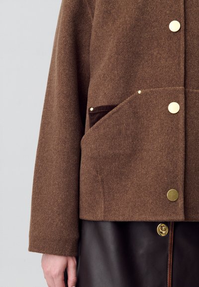 Veste en mélange de laine marron avec une surface texturée, dotée d'une grande poche avant, de quincaillerie dorée et d'une poche en velours côtelé contrastante.