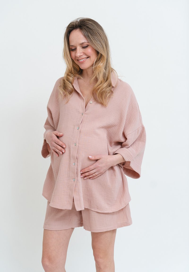 Světle růžový, texturovaný set loungewear z bavlny, který obsahuje volnou košili na knoflíky s širokými rukávy a odpovídající šortky.