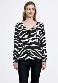 Blusa a maniche lunghe a righe zebrate in bianco e nero con scollo a V, cordini al collo e polsini elastici. Tessuto dalla superficie liscia.