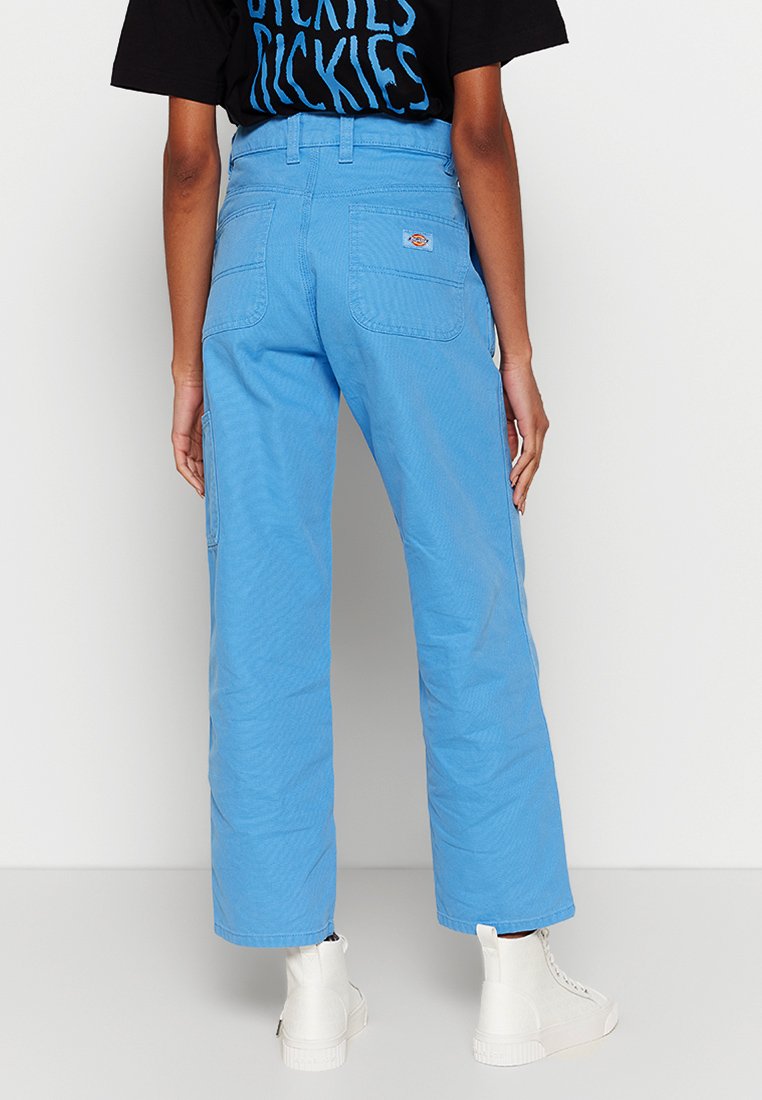 Pantaloni a gamba larga di colore azzurro chiaro realizzati in tessuto resistente. Presentano due tasche posteriori e un piccolo logo del brand sulla tasca destra.