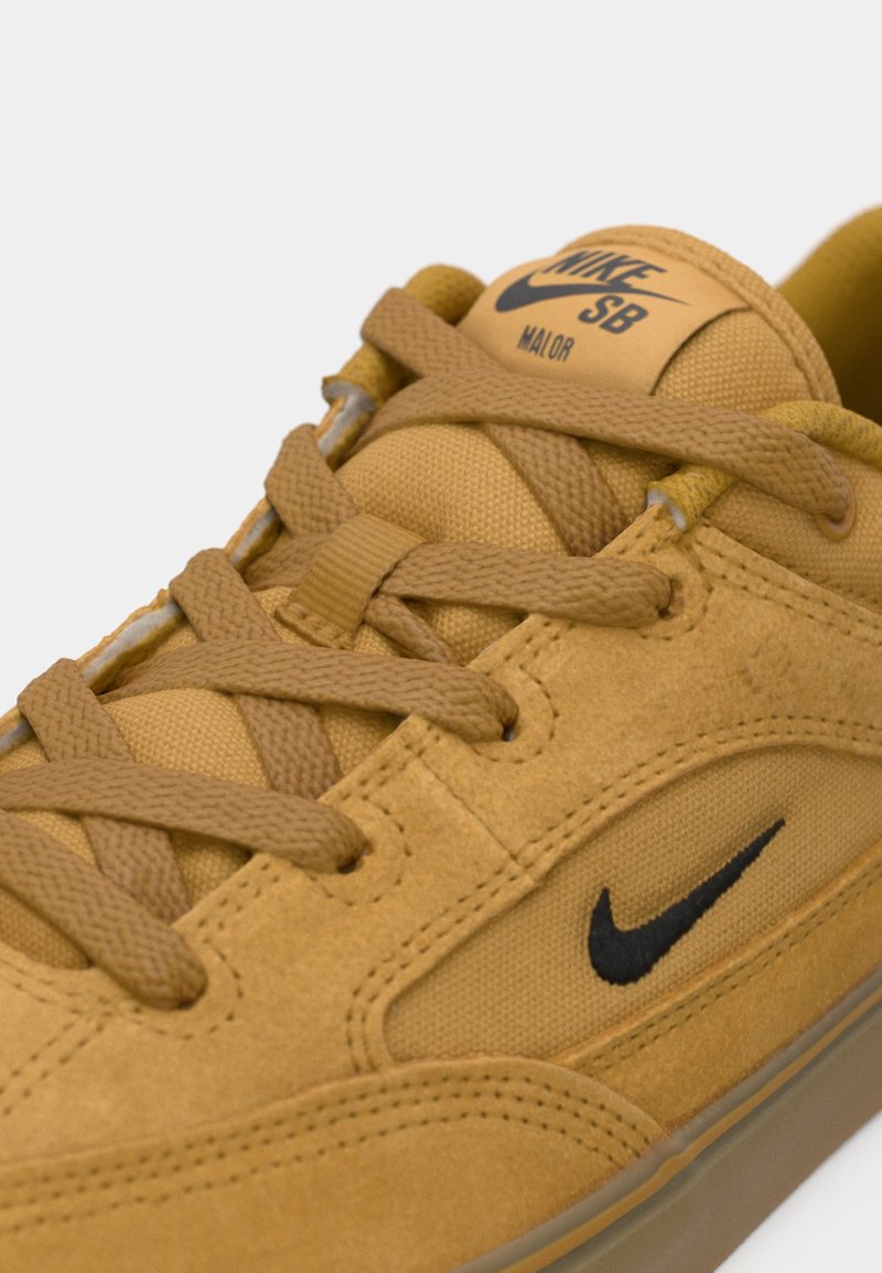 Baskets Nike SB Major en suede beige et toile, avec des lacets plats, un logo Swoosh noir et une languette rembourrée pour le confort.