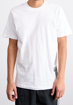 Biała bawełniana koszulka z krótkim rękawem, okrągłym dekoltem i czarną metką Adidas na dolnej lewej stronie. Gładka tekstura, klasyczny krój.