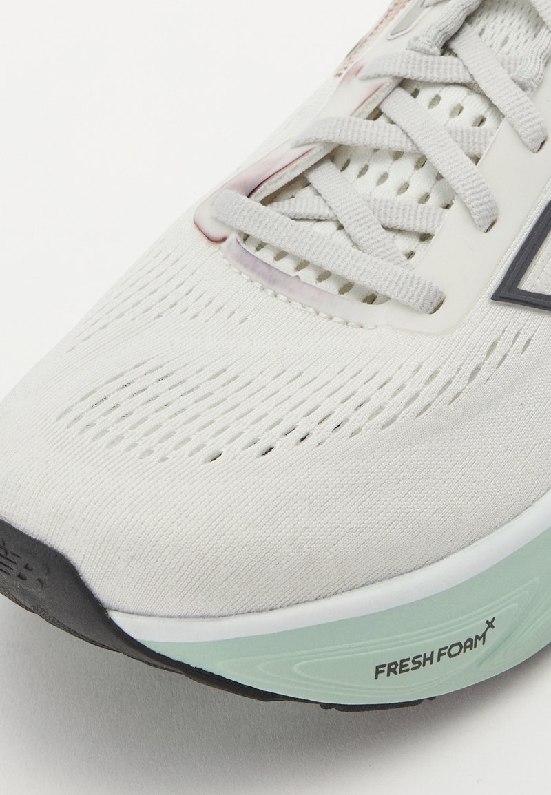 Zapatilla deportiva blanca con una parte superior texturizada y transpirable, cordones planos y una suela de espuma verde claro con la marca "FRESH FOAM".