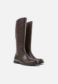 Botas de cuero marrón hasta la rodilla con una textura suave, punta redondeada y diseño minimalista. Con una suela plana para mayor comodidad.