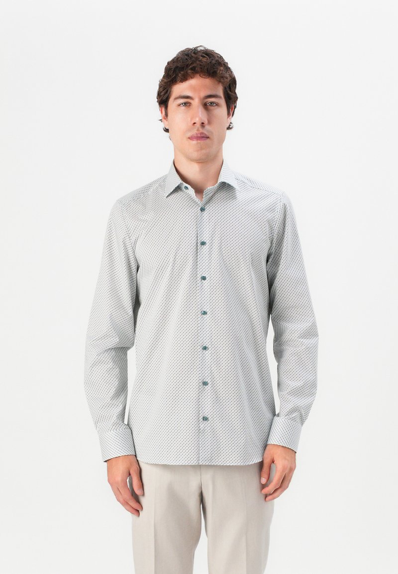 Long-sleeve shirt in light green cotton with a subtle geometric pattern. Features a button-up front and a left chest pocket. Buttons are dark teal.