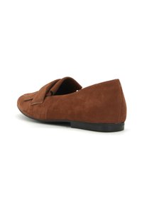 Mocassino in suede marrone con un ampio vamp piegato. Presenta una suola piatta e una punta arrotondata, mettendo in mostra una texture liscia e un design minimalista.