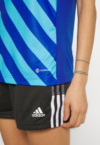 Blau- und türkisgestreiftes Sporthemd mit dem 'AEROREADY'-Logo, kombiniert mit schwarzen Shorts, die weiße Adidas-Streifen und Logo aufweisen.