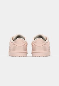 Pink leather sneakers with a smooth texture, rounded edges, padded collar, and a subtle logo on the heel. Rubber sole with traction tread.