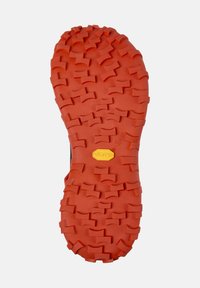 Červená Vibram podešev s texturovaným povrchem, obsahující rozmanité geometrické vzory pro trakci. Kulatý logo připevněné v blízkosti oblasti paty.