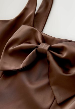 Ruskea satiinimekko, jossa suuri rusetti edessä ja leveät olkaimet. Kangas on sileä ja kiiltävä, ja siinä on pehmeät laskokset.