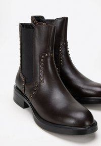 Brązowe skórzane botki za kostkę z elastycznymi panelami bocznymi, ćwiekowanymi detalami wzdłuż szwów oraz minimalistycznym, blokowym obcasem.