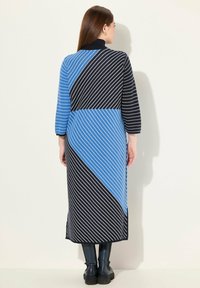 Abito lungo con pannelli diagonali blu e neri con strisce bianche. Collo rotondo, maniche lunghe e design alla caviglia. Tessuto a maglia texturizzato.