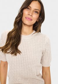Helle beige gestrickte Sweater mit kurzen Ärmeln, der über eine strukturierten Diamantmuster-Optik und einen Rundhalsausschnitt verfügt. Strukturierter und atmungsaktiver Stoff.