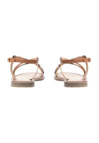Sandali piatti marroni con sottili cinturini e una decorazione sul retro. Le suole sono lisce con un leggero tacco, adatte per un uso casual.