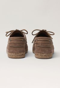 Brown suede espadrilles with lace-up closures and stitched accents. Jute rope sole enhances texture, providing a casual appearance.