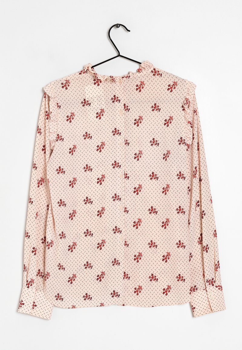 Skjorta med långa ärmar i ljusrosa tyg med röd blommönster och kontrasterande diamantskärning. Har en volangkrage och volang vid ärmsluten.
