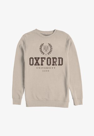 Sweat-shirt beige avec le texte "Oxford University 1231" et un emblème de couronne de laurier et bouclier imprimé en marron foncé à l'avant.