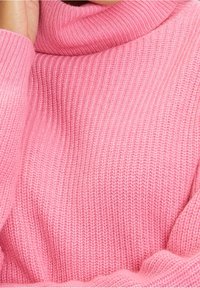 Rosa gestrickter Pullover mit hohem, umgeschlagenem Kragen. Der Stoff zeigt eine gerippte Textur und vermittelt ein weiches und gemütliches Aussehen.