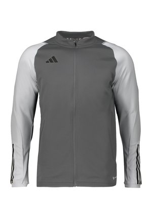 Szara sportowa kurtka z pełnym zamkiem na przodzie, kontrastowymi jasnoszarymi rękawami i czarnymi paskami na rękawach. Zawiera logo Adidas.