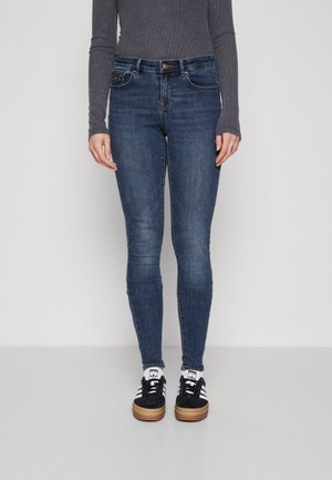 Smalte jeans i mørkeblå denim med en lett falmet vask. Har midjehøyde, klassisk fem lommers design og knappelukking.