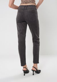Pantaloni in corduroy grigi con vestibilità slim, dotati di cinque tasche e vita medio-alta. Texture liscia con righe verticali.
