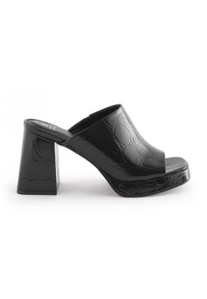 Mule noire à talon haut avec une large bride à motif crocodile, talon bloc et bout ouvert, présentée sur fond blanc.