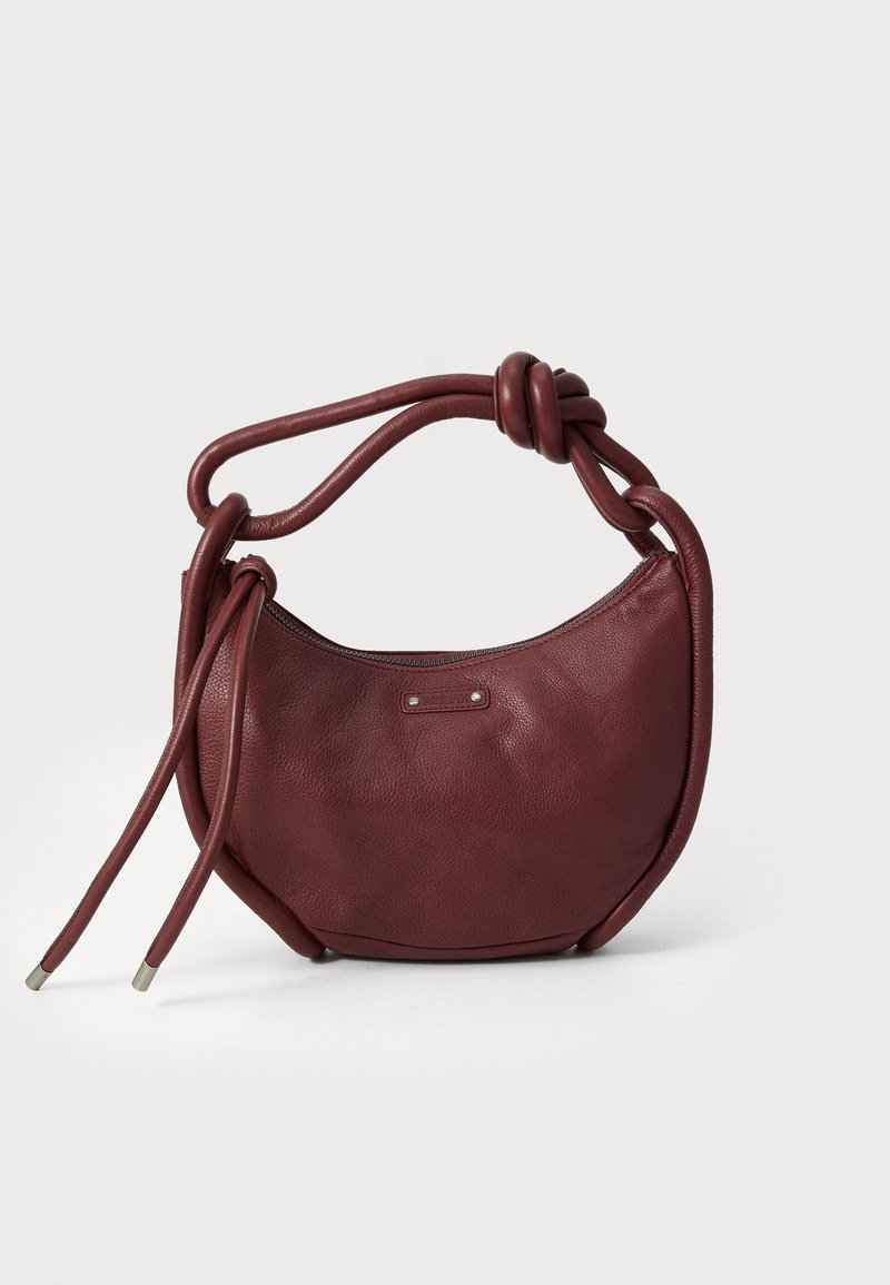 Bolso de cuero burdeos con forma redondeada, asa anudada y dos correas largas. Superficie texturizada con cierre de cremallera y detalle de logo.
