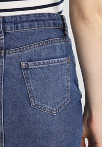 Blauwe denim jeans met een rechte pasvorm, voorzien van een enkele achterkantzak met verstevigde stiksels en een textuurstofafwerking.
