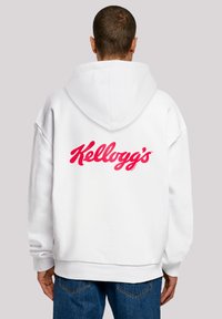 Weißer Hoodie mit Kapuze und Kordelzug, auf der Rückseite mit einem großen roten "Kellogg's"-Logo versehen. Das Material wirkt weich und hat einen lässigen Schnitt.