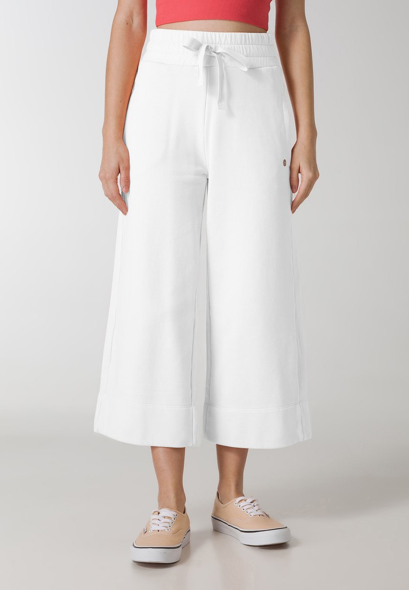 Pantaloni in cotone bianco a gamba larga con vita elasticizzata e cordoncino. Presentano orli cuciti e un dettaglio logo discreto sul lato.