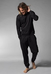 Schwarzes Sweatshirt und passende Jogginghose aus weichem Stoff, mit lockerer Passform, gerippten Bündchen und elastischem Bund.