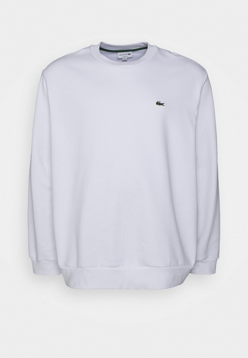 Witte sweatshirt van zachte stof, met een ronde hals, lange mouwen en een klein groen Lacoste-logo op de borst.