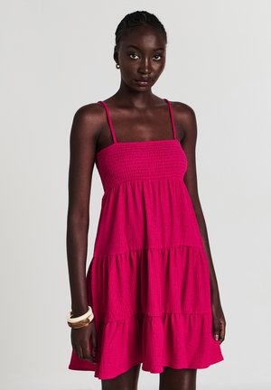 Fuchsia schichtetes Kleid mit quadratischem Ausschnitt und dünnen Trägern. Strukturierter Stoff mit gerafftem Oberteil. Keine Verzierungen.