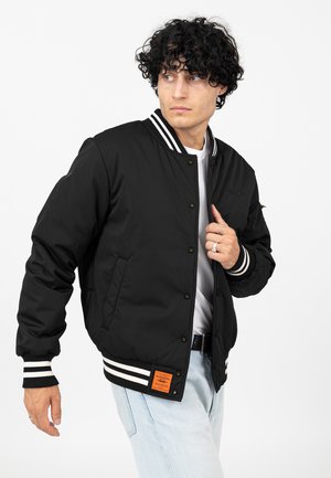 Black padded bomber jacket with striped ribbed collar and cuffs. Features front snap buttons, side pockets, and an orange label on the hem.