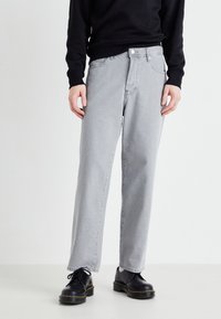 Gray denim jeans with a loose fit, featuring classic five-pocket design, a front button, and zipper closure, paired with black shoes.