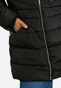 Čierna puffová bunda s horizontálnym prešívaním, zlatým zipsom, bočnými vreckami a elastickými manžetami, ktorých hladká a lesklá tkanina sa elegantne vyníma.