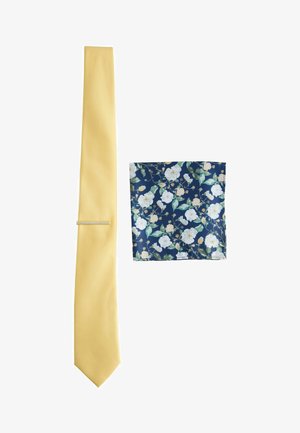Solide hellgelbe Krawatte mit einem marineblauen Einstecktuch, das weiße und hellrosa Blumenmuster zeigt.