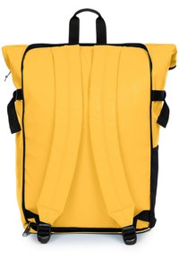 Mochila amarilla con respaldo acolchado, cremalleras negras y correas ajustables. Cuenta con un asa en la parte superior y un diseño elegante y aerodinámico.