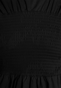 Vestido preto com corpete franzido e bainha evasê. A textura suave com detalhes franzidos acrescenta interesse visual.