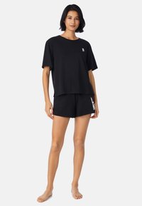 Czarny bawełniany t-shirt o luźnym kroju i krótkich rękawach, w połączeniu z czarnymi szortami z białą grafiką. Gładka tekstura, casualowy design.