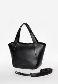 Zwarte leren tote bag met twee korte handvatten, een slank ontwerp, gladde textuur en een afneembare schouderband. Minimalistische branding aan de zijkant.