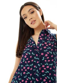 Navy blouse with pink cherry print, short collar, button details, and a relaxed fit. Fabric appears lightweight and textured.