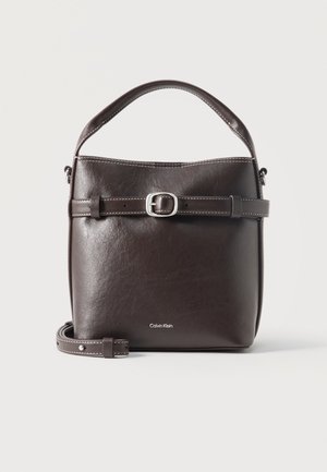 Mørkebrun læder bucket taske med justerbar spænde strop, top håndtag og Calvin Klein-logo foran.