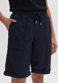 Granatowe szorty z bawełny, z elastycznym paskiem do regulacji, z podwiniętymi nogawkami oraz dwiema bocznymi kieszeniami z delikatnymi detalami haftu.