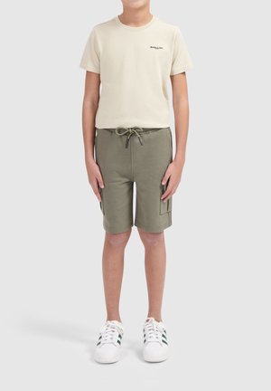Beige katoenen t-shirt met "BALLIN" logo, olijfgroene shorts met een trekkoord en zijzakken, gecombineerd met witte sneakers met groene strepen.